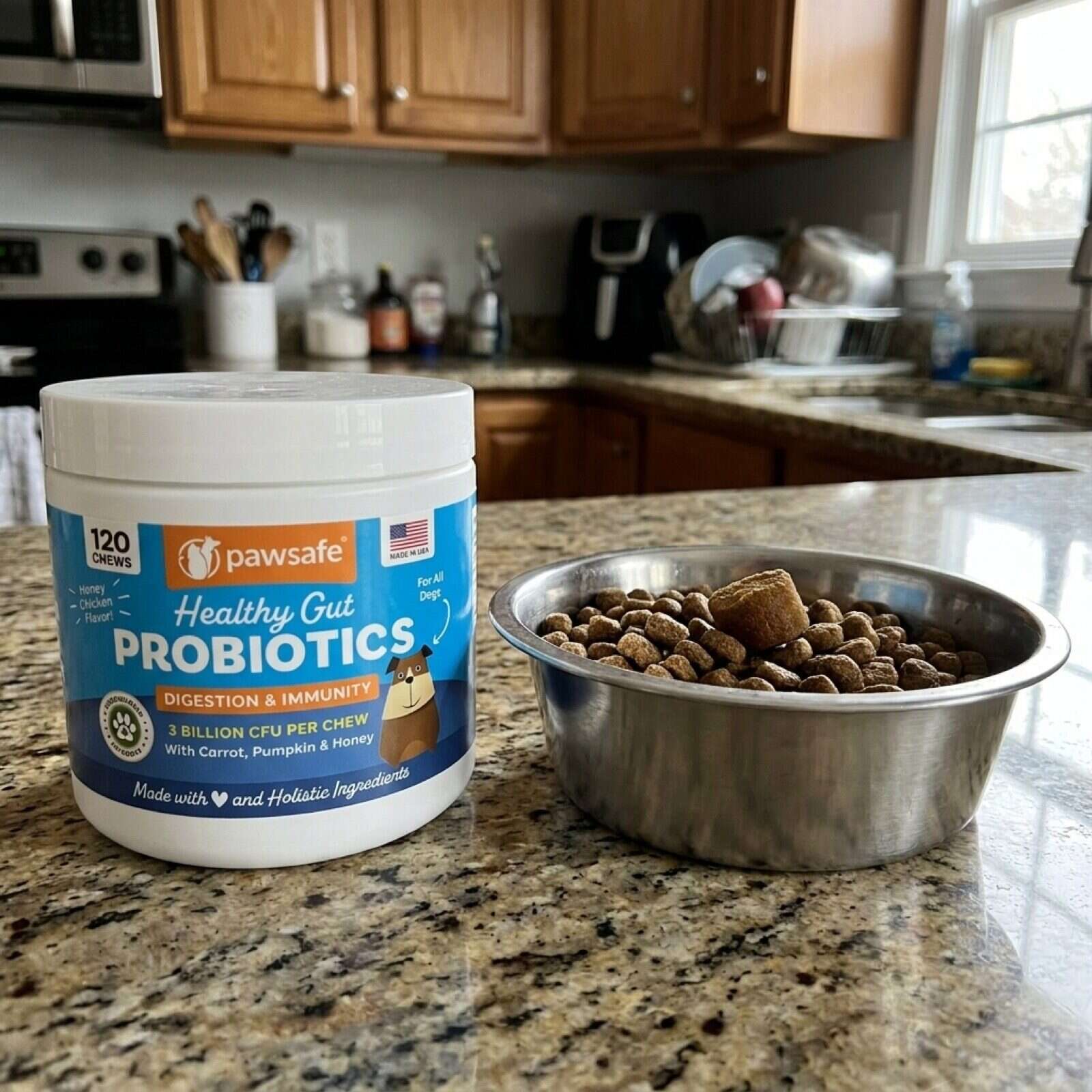 A tub of PawSafe Healthy Gut Probiotic Soft Chews on a morning kitchen counter beside a full dog bowl with one chew resting on top of the kibble
